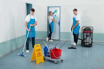 Group Of Janitors Cleaning Corridor With Cleaning Equipments